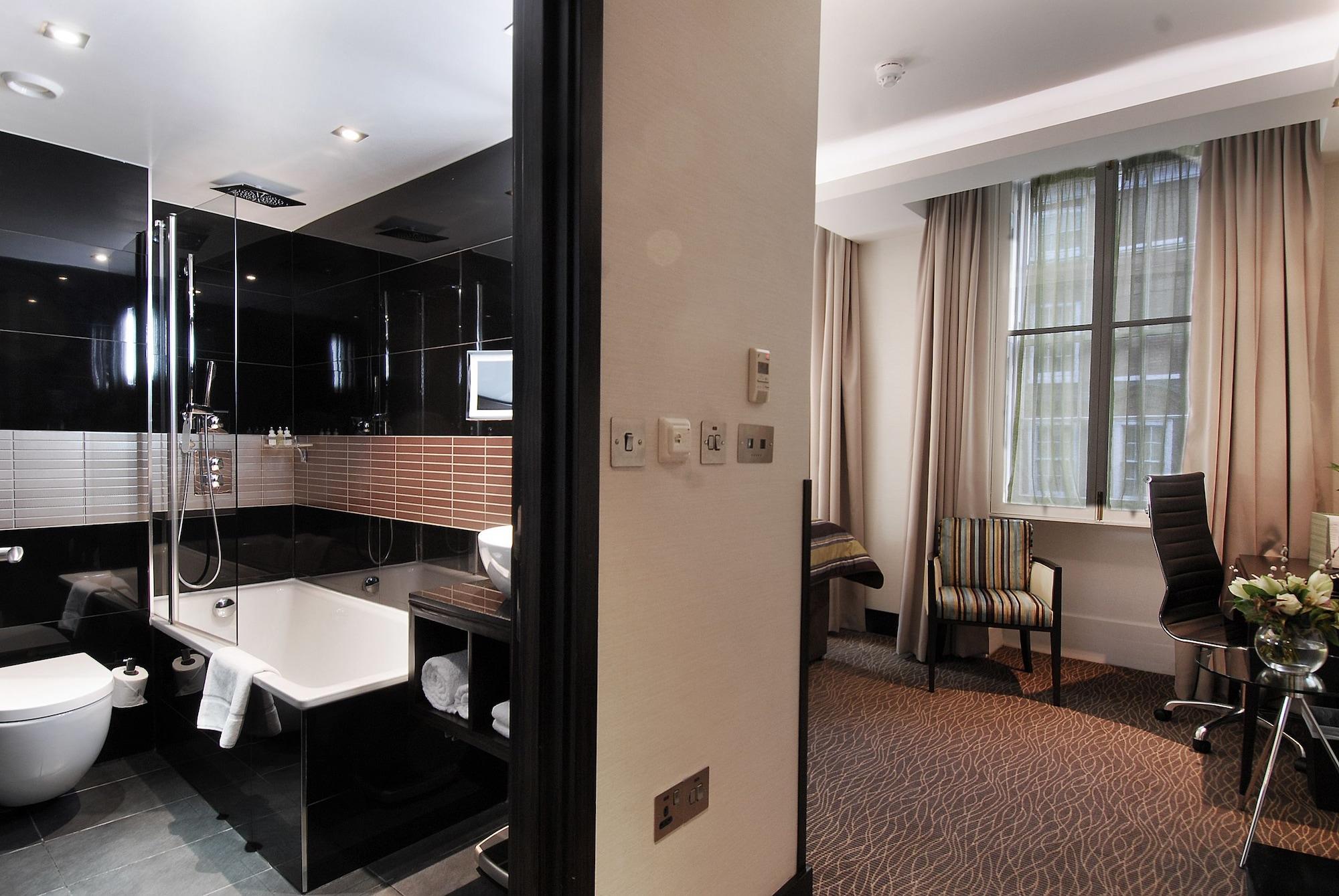 فندق Montcalm Brewery Townhouse لندن المظهر الخارجي الصورة The photo shows a modern hotel room that features an elegant bathroom on one side and a living area on the other. 

1. **Bathroom**: The bathroom is stylishly designed with a combination of black and white tiles. It includes a bathtub, a shower area 