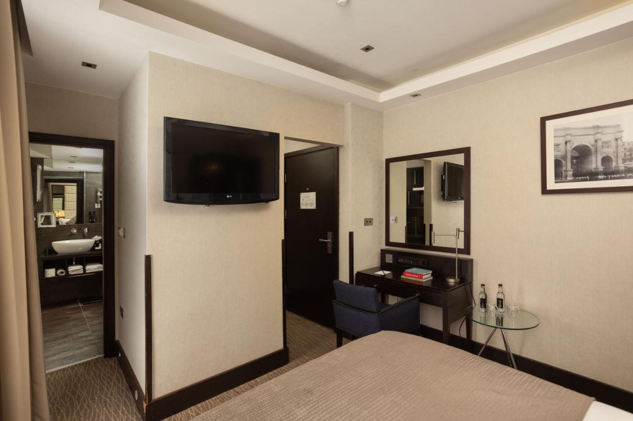 فندق Montcalm Brewery Townhouse لندن المظهر الخارجي الصورة The photo shows a hotel room featuring a double bed with a neutral-colored bedspread. On one wall, there is a flat-screen TV mounted. Adjacent to the bed, there is a stylish desk with a chair and a small glass table. A mirror is positioned above the 