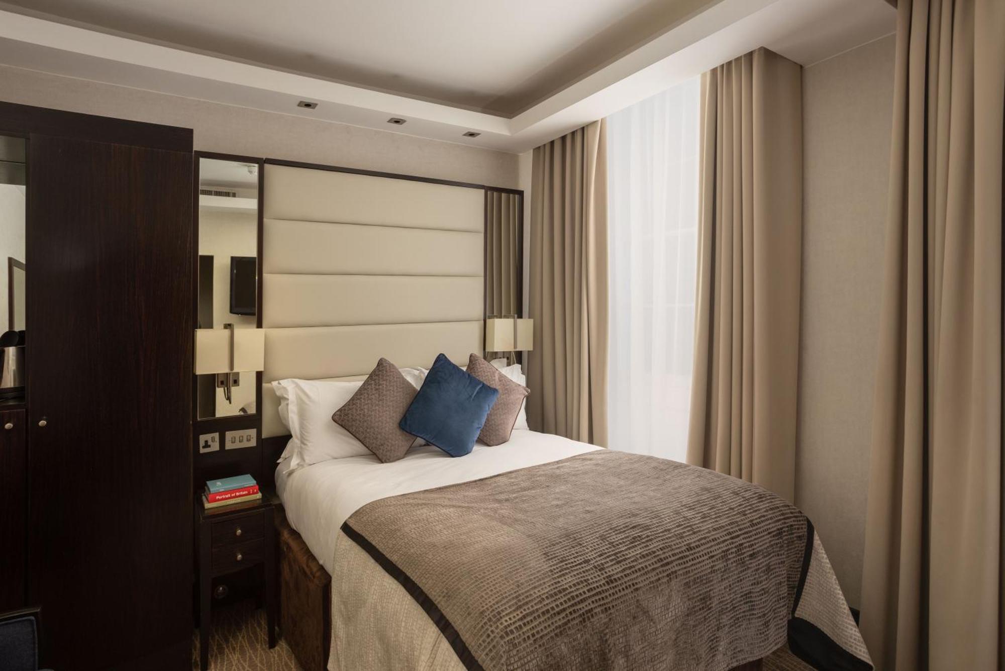 فندق Montcalm Brewery Townhouse لندن المظهر الخارجي الصورة The photo shows a modern hotel room with a cozy design. It features a double bed with a light-colored headboard and a soft, stylish blanket. There are decorative pillows on the bed, including a blue one. On either side of the bed, there are small nig