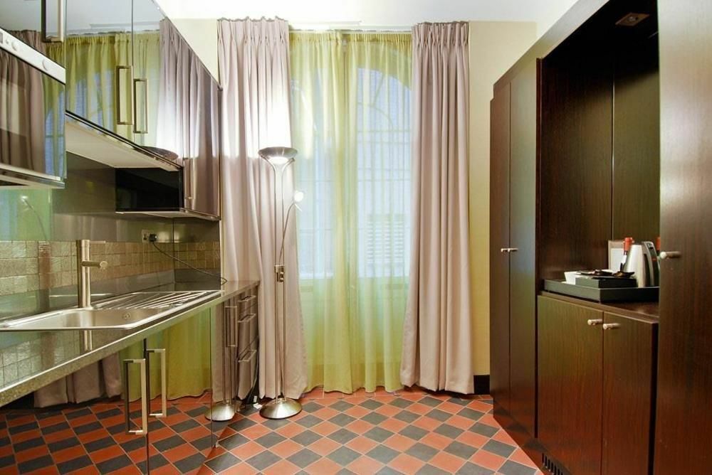 فندق Montcalm Brewery Townhouse لندن المظهر الخارجي الصورة The photo shows a modern kitchen area. There is metallic cabinetry and a stainless steel countertop with a sink. The walls are adorned with light-colored curtains that allow natural light to filter in, with one set in a soft purple hue and another in